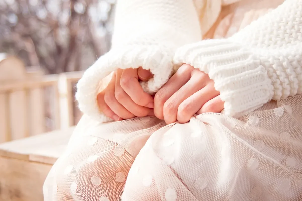 Close-up of hands tightly clasped together, fidgeting with fabric, reflecting nervous tension and anxiety