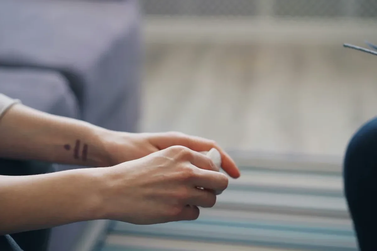 Couple holding hands during a counselling session, with a medical patient information clipboard in the foreground