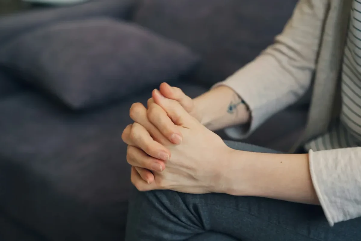 Client's hands clasped together during a therapy session